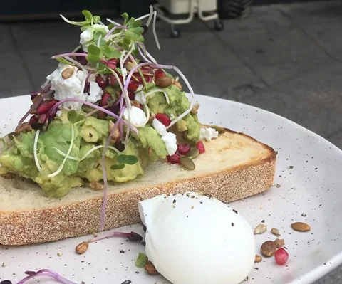 Smashed avo on thick toast with microgreens, feta and a poached egg, at a café in Melbourne